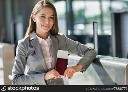 Portrait of young attractive businesswoman holding her passport and boarding pass in airport