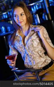 Portrait of young attractive woman in night club with a drink