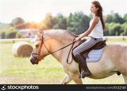 Portrait of young attractive woman riding horse in ranch