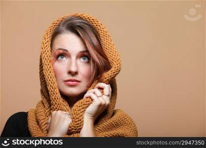 Portrait of young autumnal woman in warm scarf. Fresh girl with glamour makeup false long orange eyelashes. Brown background. Studio shot.