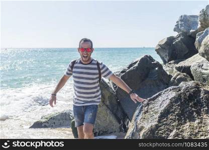 Portrait of young bearded man standing on seashore in a sunny day