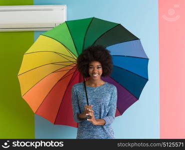 Portrait of young beautiful african american woman holding a colorful umbrella isolated on a Colorful background