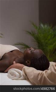 Portrait of young beautiful african woman in spa environment getting massage