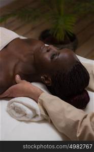 Portrait of young beautiful african woman in spa environment getting massage