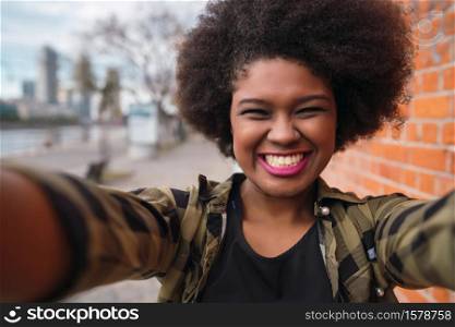 Portrait of young beautiful afro american woman taking a selfie outdoors in the street.