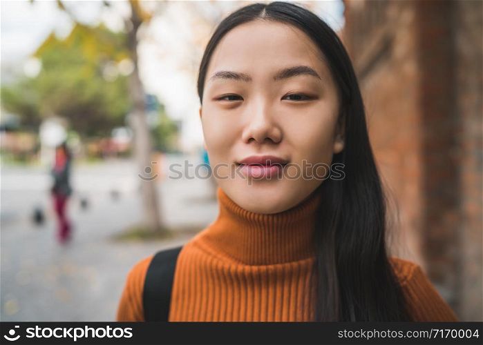 Portrait of young beautiful Asian woman standing outdoors in the street. Urban concept.