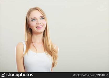 Portrait of young beautiful blonde woman smiling and looking up on gray background