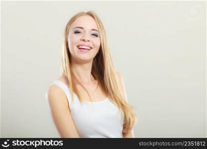 Portrait of young beautiful blonde woman smiling on gray background