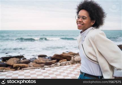 Portrait of young beautiful latin woman enjoying fresh air with the sea on the background.