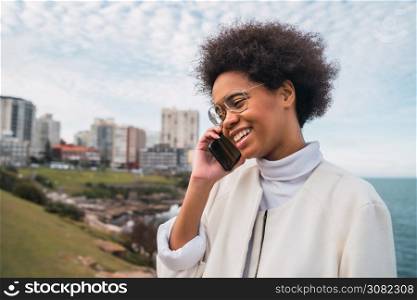 Portrait of young beautiful latin woman talking on the phone outdoors. Communication concept.