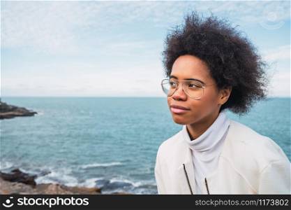 Portrait of young beautiful latin woman with thoughtful expression with the sea on the background.