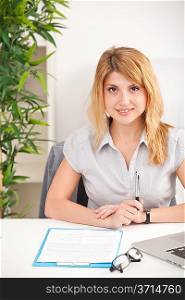 Portrait of young beautiful smiling woman sitting in her workplace