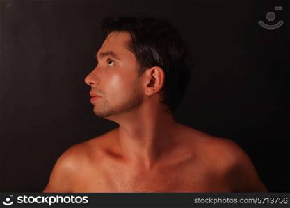 Portrait of young beautiful tanned guy on black background