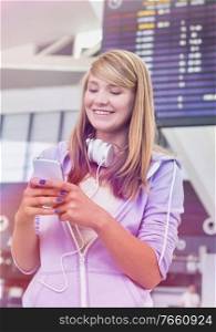 Portrait of young beautiful teenage girl using smartphone in airport with lens flare