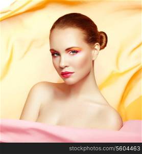 Portrait of young beautiful woman against flying fabric. Beauty woman face closeup. Professional makeup