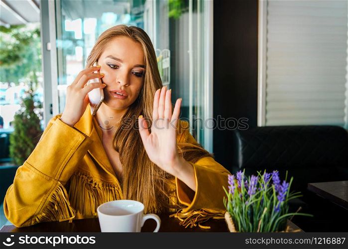 Portrait of young beautiful woman at cafe restaurant talking to the mobile phone call receiving disturbing surprising news