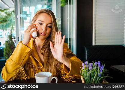 Portrait of young beautiful woman at cafe restaurant talking to the mobile phone call receiving disturbing surprising news