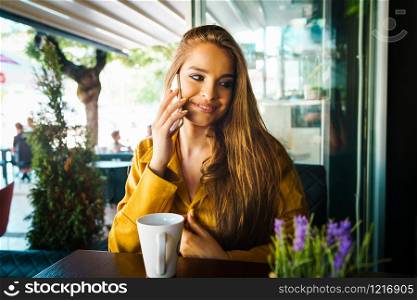 Portrait of young beautiful woman at cafe restaurant talking to the mobile phone call happy smiling