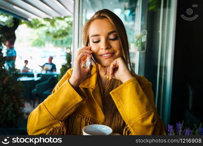 Portrait of young beautiful woman at cafe restaurant talking to the mobile phone call happy smiling