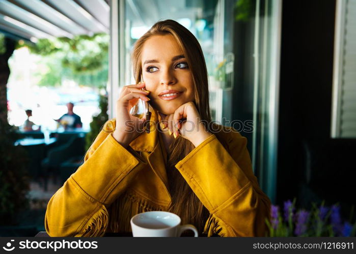 Portrait of young beautiful woman at cafe restaurant talking to the mobile phone call happy smiling