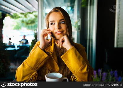 Portrait of young beautiful woman at cafe restaurant talking to the mobile phone call happy smiling
