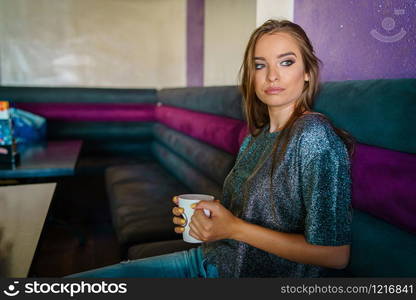 Portrait of young beautiful woman girl sitting alone at cafe having a cup of coffee or tea