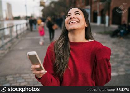 Portrait of young beautiful woman holding her mobile phone with successful expression, celebrating something. Success concept.