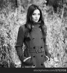 Portrait of young beautiful woman in autumn coat. Fashion photo. Black and white