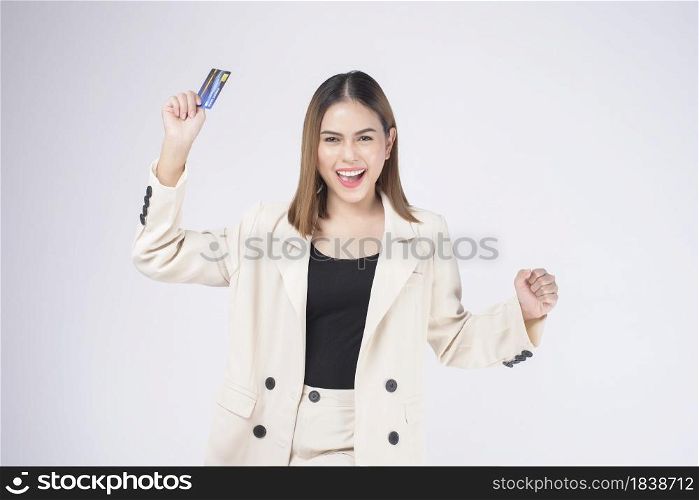 Portrait of Young beautiful woman in suit holding credit card over white background in studio