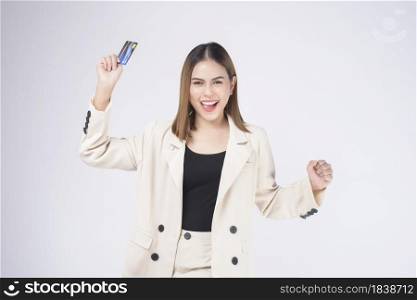 Portrait of Young beautiful woman in suit holding credit card over white background in studio