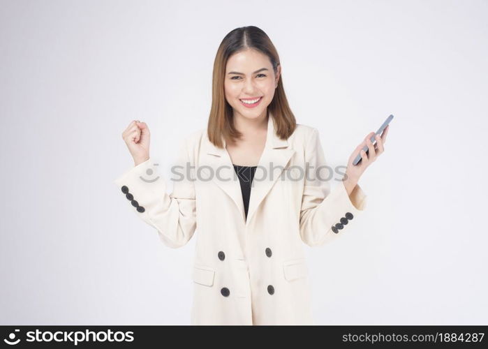 Portrait of young beautiful woman in suit using smart phone over white background