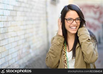 Portrait of young beautiful woman in urban background hearing music with headphones