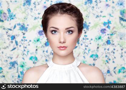 Portrait of young beautiful woman on a background of flowers. Fashion photo. Jewelry and hairstyle. Perfect makeup