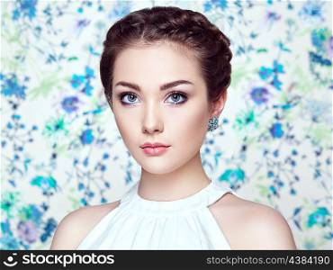 Portrait of young beautiful woman on a background of flowers. Fashion photo. Jewelry and hairstyle. Perfect makeup