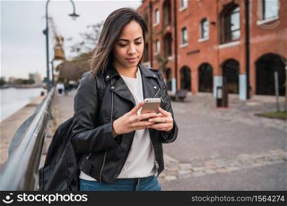 Portrait of young beautiful woman using her mobile phone outdoors in the street. Urban and communication concept.