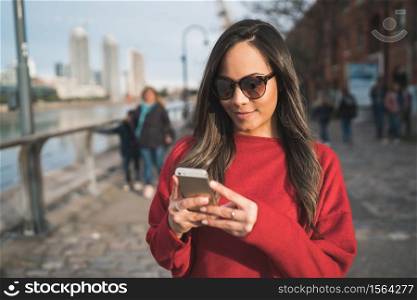 Portrait of young beautiful woman using her mobile phone outdoors in the street. Urban and communication concept.
