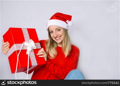 Portrait of young beautiful woman wearing christmas hat and holding a present on studio.
