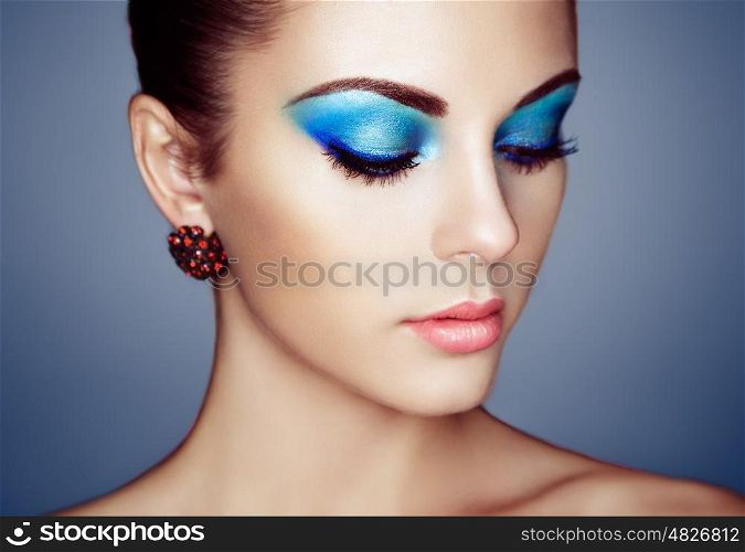 Portrait of young beautiful woman with blue makeup. Face Girl with earring close up. Fashion jewelry