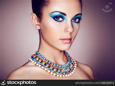 Portrait of young beautiful woman with blue makeup. Face Girl with necklace close up. Fashion jewelry