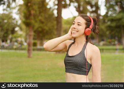 Portrait of young beautiful woman with red headphones listening music. Outdoors. Urban concept.. Young beautiful woman with red headphones listening music
