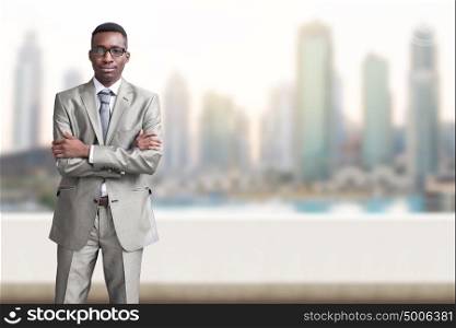 Portrait of young black businessman standing on balcony in front of the big city
