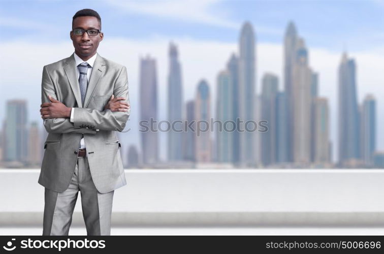 Portrait of young black businessman standing on balcony in front of the big city