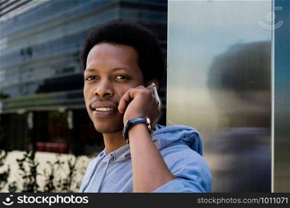 Portrait of young black man talking on mobile phone outside.