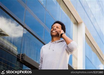 Portrait of young black man talking on mobile phone outside.