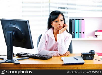 Portrait of young black unhappy business woman at desk in office