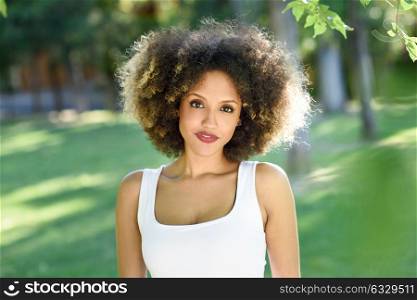 Portrait of young black woman with afro hairstyle in urban park. Mixed girl wearing casual clothes.
