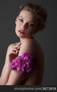 portrait of young blond elegant woman with some carnation purple flower around one arm