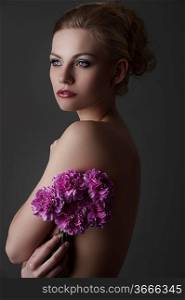 portrait of young blond naked woman with some carnation purple flower