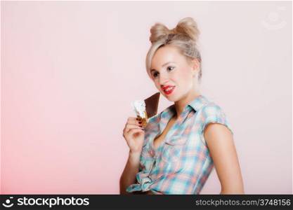 Portrait of young blonde chocolate loving beauty. Sexy girl eating holding chocolate bar on pink background.