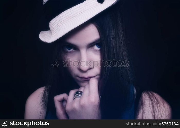 Portrait of young blue-eyed girl in white hat on black background
